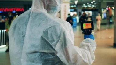 Sağlık çalışanı halka açık bir yeri termal kamerayla tarıyor.