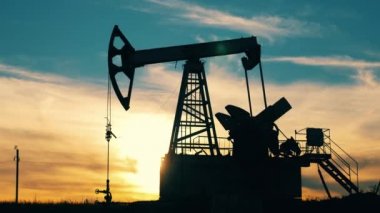 Gün batımında petrol çıkaran bir pompacının hızlı hareketi. Ham petrol, gaz, petrol fiyatları kavramı.