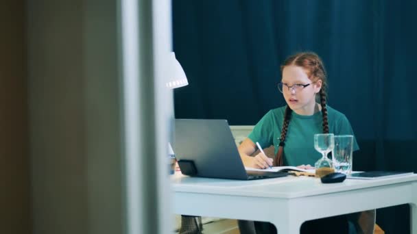 Una ragazza sta studiando con un computer portatile e prende appunti — Video Stock