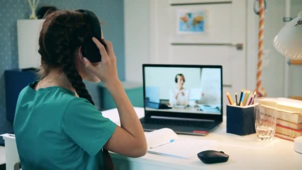 Tiener meisje zet op hoofdtelefoon tijdens een online les — Stockvideo