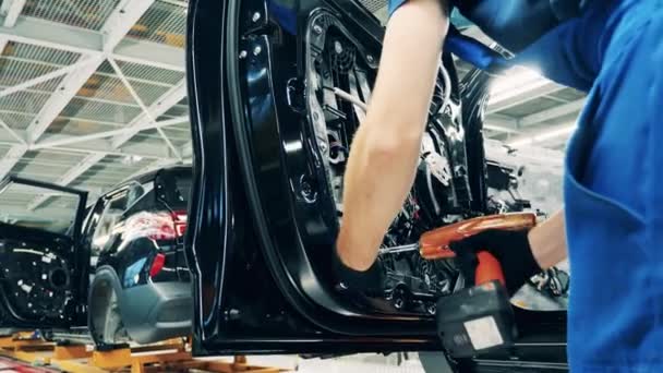 Mechaniker montiert mit einem Elektroschrauber eine Autotür — Stockvideo