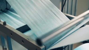 Tıbbi maske üretim tesisinde kumaş şekillendiren modern makine.