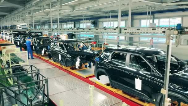 Personas que trabajan en un transportador en la fábrica de automóviles. Industria automotriz, línea de producción de automóviles. — Vídeo de stock