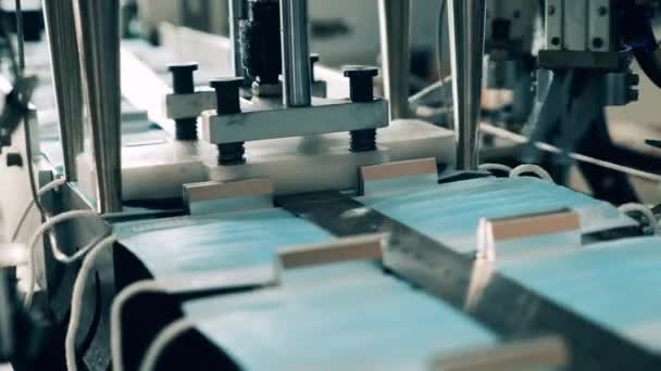 Ohrschlaufenbefestigungsmaschine in einer Produktionsstätte für medizinische Masken. Coronavirus-Schutzmasken-Produktionslinie. — Stockvideo