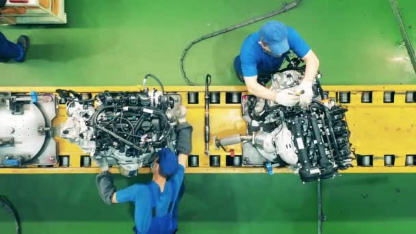 Trabajadores que ensamblan motores de automóviles en una fábrica industrial. — Vídeo de stock