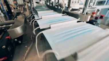 Yüz maskeleri taşıyıcı bant boyunca hareket ediyor. Coronavirus koruma maskesi üretim hattı.