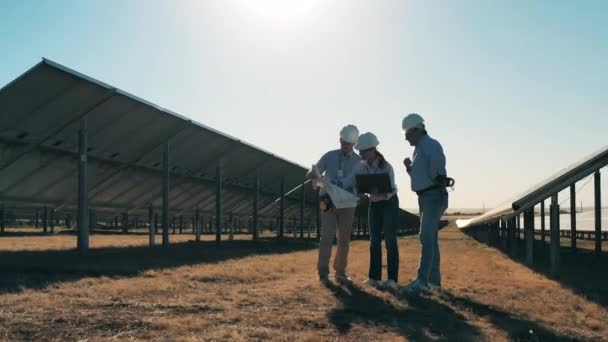 Güneş enerjisi kavramı. Üç güneş enerjisi uzmanı güneş parkında tartışıyorlar. — Stok video