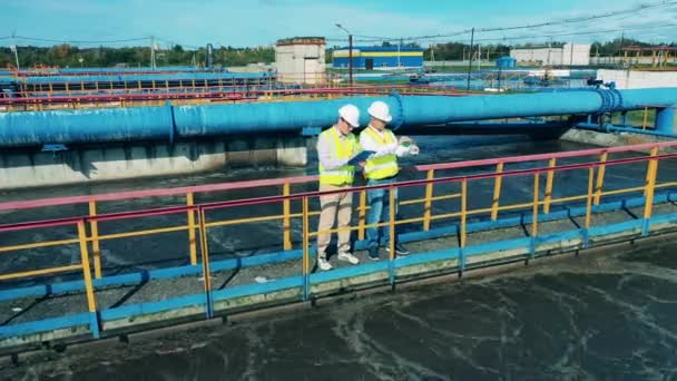 Mannelijke technici bespreken rioolwaterzuiveringsinstallaties — Stockvideo