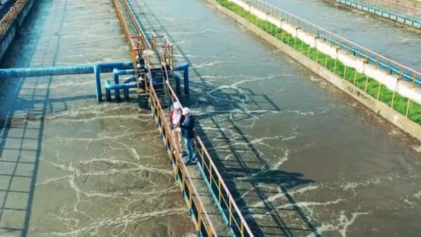 Local de limpeza de águas residuais com dois técnicos filmados de cima — Vídeo de Stock