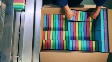 Fabrika işçisi süngerleri bir kutudan taşıyıcıya taşıyor.