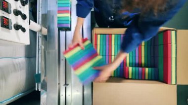 Kadın işçi bir kutudan konveyör bandına sünger yerleştiriyor.