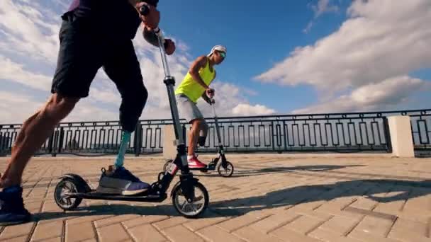 Люди с протезными ногами ездят на скутерах вместе — стоковое видео