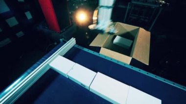 Robot makine taşıyıcıdan küçük kutuları çıkarıyor.