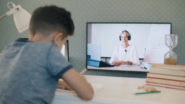 Küçük okul çocuğu televizyonunu kullanarak evden uzaktan çalışıyor. — Stok video