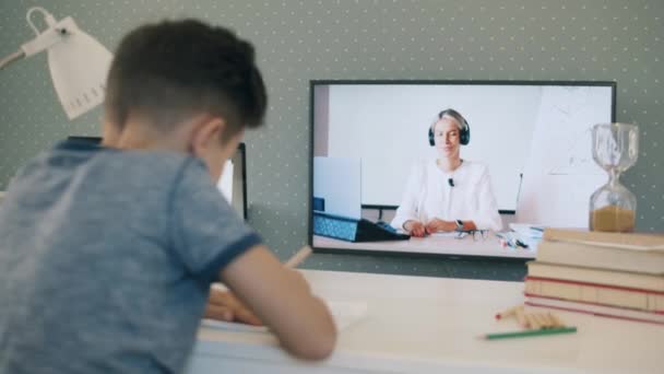 Pequeño colegial estudiando remotamente desde casa usando su TV — Vídeos de Stock