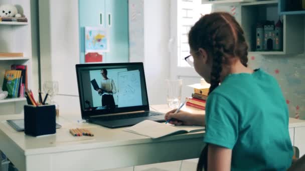 Écolière étudiant à distance à la maison à l'aide d'un ordinateur portable. Enseignement à distance causé par le verrouillage covid-19. — Video