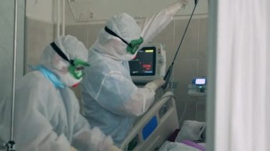 Covid-19 koruma giysileri içindeki doktorlar koronavirüslü bir hastaya yardım ediyorlar. Coronavirüs salgını, covid-19 konsepti.