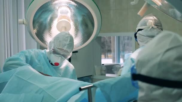Zdravotničtí pracovníci v bezpečnostních oblecích podstupují operaci — Stock video