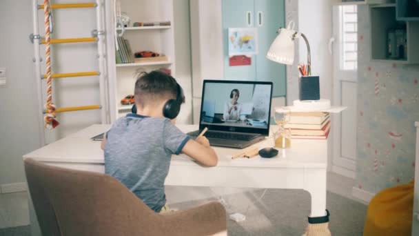 Petit enfant étudiant en ligne devant son ordinateur portable à la maison. Enseignement à distance causé par le verrouillage covid-19. — Video