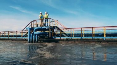 İki mühendis kanalizasyon arıtma alanını inceliyor.