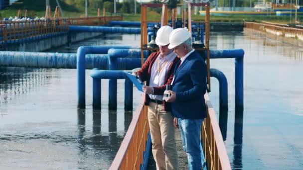 Mannelijke collega 's discussiëren over rioolwaterzuiveringsinstallaties buiten — Stockvideo