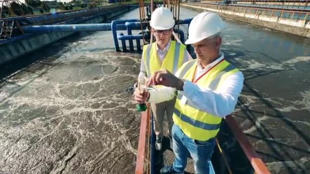 Los inspectores están analizando una muestra de agua en el sitio de limpieza de aguas residuales — Vídeos de Stock
