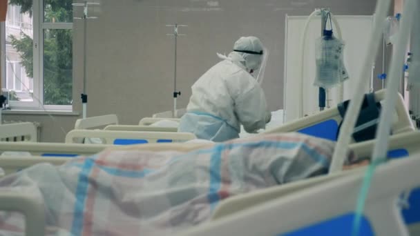 Un médecin en combinaison de sécurité prend soin du patient atteint du coronavirus dans une clinique covid-19. — Video