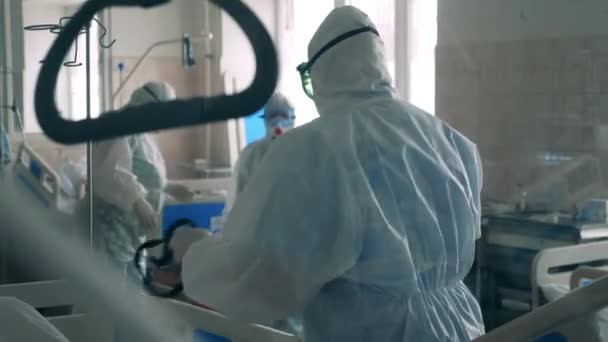 Grupo de médicos con trajes de seguridad en una sala de hospital covid-19, unidad de atención de emergencia coronavirus. — Vídeos de Stock