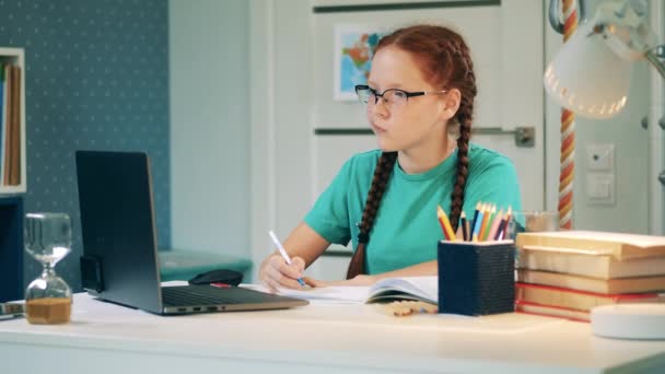 Konzentrierte Schülerin im Gespräch mit einem Lehrer aus der Ferne mit einem Laptop — Stockvideo