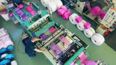 Fabrika işçisi plastik torba üretim makinesini izliyor.