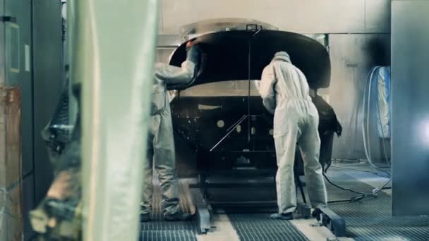 Trabalhadores da fábrica pulverizam a pintura de um corpo de carro em uma fábrica de produção de carro — Vídeo de Stock