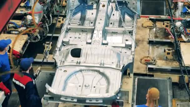 Zwei Arbeiter einer Autofabrik bewegen eine Karosserie mit Ketten — Stockvideo