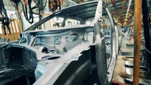 Närbild av en bilkaross som rör sig längs en produktionslinje vid en bilfabrik — Stockvideo