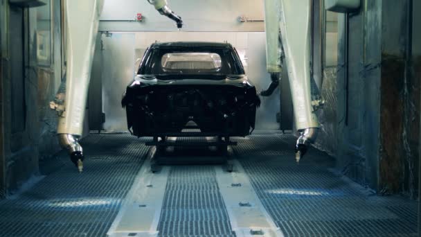 Robots pintando un cuerpo de coche negro en una fábrica de producción de automóviles — Vídeo de stock