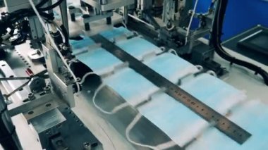 Yüz maskeleri ölçülürken konveyör boyunca hareket ediyor