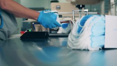 Fabrika işçisi taşıyıcıya yeni tıbbi maskeler yüklüyor.