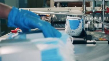 İşçi tıbbi maskeleri paketleme makinesine koyuyor.