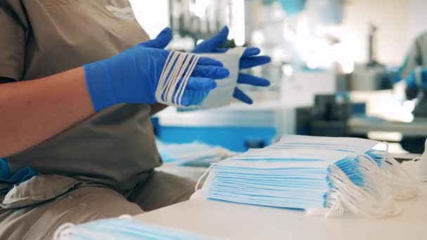 Работник завода проверяет и собирает медицинские маски — стоковое видео
