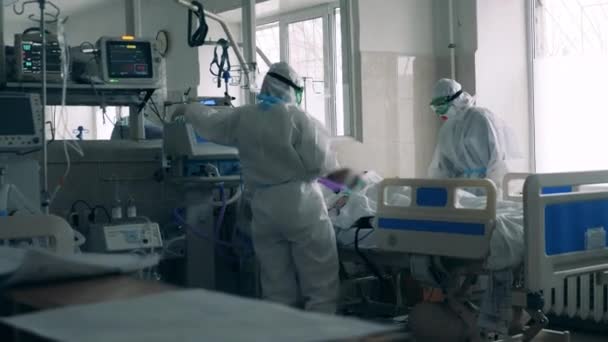 Deux travailleurs de la santé soignent un patient atteint du coronavirus dans un lit de soins intensifs — Video