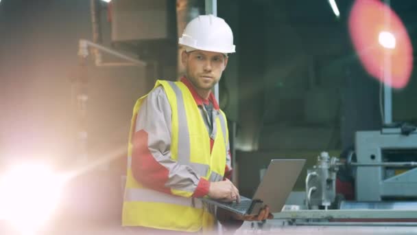 Ingeniero masculino con un ordenador portátil está observando equipos de metalurgia — Vídeos de Stock