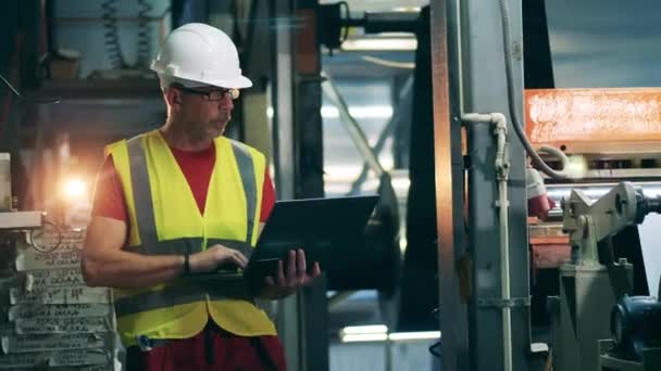 Engineer with a laptop is checking metalworking machines — Stock Video