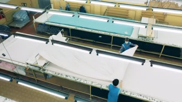 Les travailleurs de l'usine déploient une grande feuille de tissu — Video