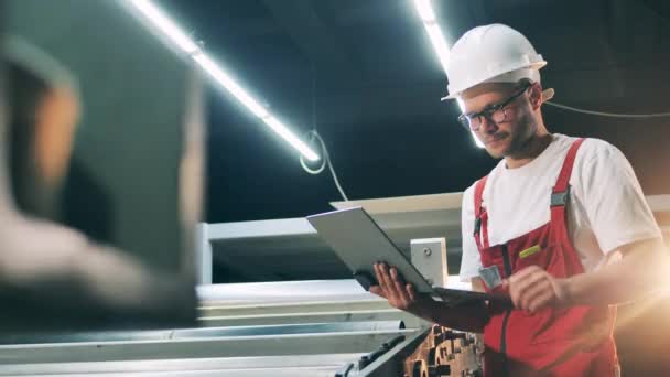 Mužský inženýr řídí tovární stroj s notebookem — Stock video