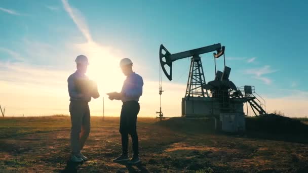 Двоє працівників нафтової галузі обговорили питання нафтового родовища — стокове відео