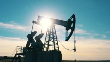 Petrol sahasında çalışan bir petrol pompacısı silueti.