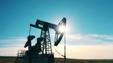 Gün ışığında çalışan bir petrol pompasının silüeti.