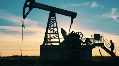 Petrol endüstrisi işçisi petrol sahasında bir petrol pompacısına doğru yürüyor.