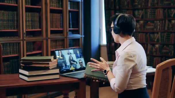 Una donna sta insegnando una lezione online da una biblioteca — Video Stock
