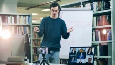 Çevrimiçi ders kütüphanede bir erkek öğretmen tarafından düzenleniyor.