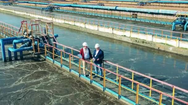 Dos empresarios inspeccionan una planta de tratamiento de aguas residuales — Vídeos de Stock